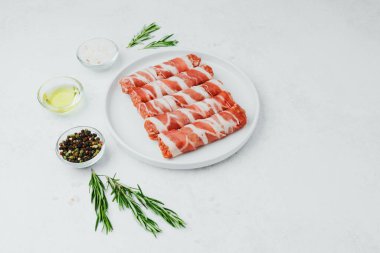 Jambona sarılmış sosis, beyaz tabakta otlar ve yağla birlikte.