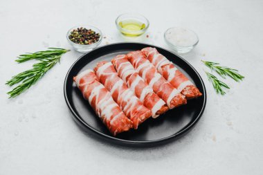 Domuz pastırması siyah tabakta baharat ve biberiye ile sarılmış.