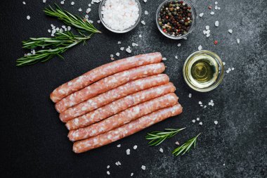 Siyah taş masada baharatlı çiğ sosisler.