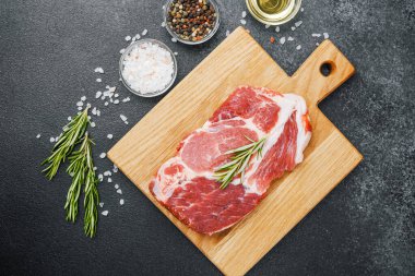 Biberiyeli çiğ biftek ve ahşap tahtada baharatlar.