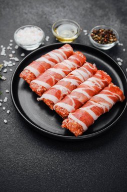 Domuz pastırmasına sarılı çiğ et ruloları ve baharatlar.