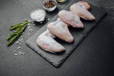 Siyah tahtada çiğ tavuk kanadı ve baharat.