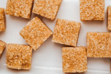 Beyaz bir yüzeye yerleştirilmiş kahverengi şeker küpleri dokularını ve şekillerini vurgular.