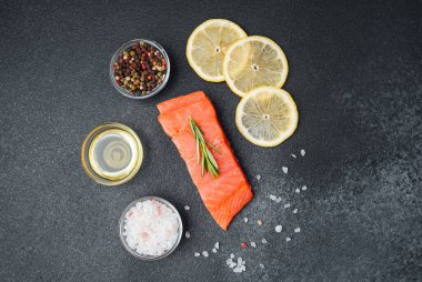 Taze somon, koyu yüzeyde limon dilimleri, baharatlar ve zeytinyağı ile düzenlenir..