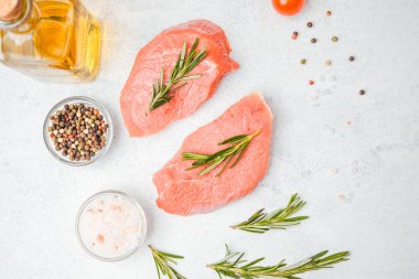 Beyaz arka planda baharatlı dana bifteği ve bitkilerin üst görüntüsü, yakın plan yağ ve biber dahil.