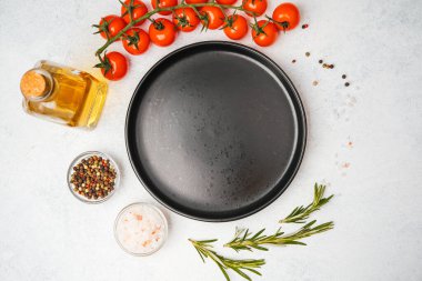 Domates, biberiye, tuz, yağ ve biber içeren yemek malzemelerinin olduğu boş siyah tabağın üst görüntüsü