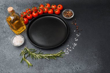 Boş siyah tabak, kirazlı domates zeytinyağı biberiye tuzu ve siyah arka planda biber.