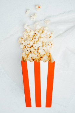 Beyaz bir yüzeye yerleştirilmiş sıcak, yumuşak patlamış mısırla dolu çizgili bir kap.