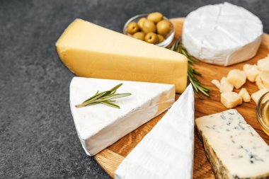 Zeytin ve otlarla ahşap bir tahtanın üzerine dizilmiş çeşitli peynirler..