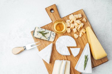 Tahtaya yerleştirilmiş çeşitli peynirler, ballı ve bıçaklı.