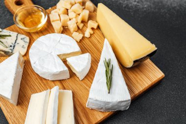 Tahta bir tahtaya yerleştirilmiş balla birlikte farklı peynirlerden oluşan bir seçim..