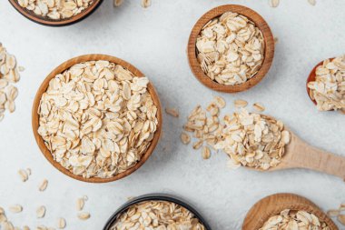 Yulaf dolu çeşitli kaseler gevşek taneli hafif bir yüzeyde sergilenir..