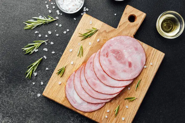 Siyah masa arkasında tuzlu ve biberiyeli dilimlenmiş domuz sosisi.