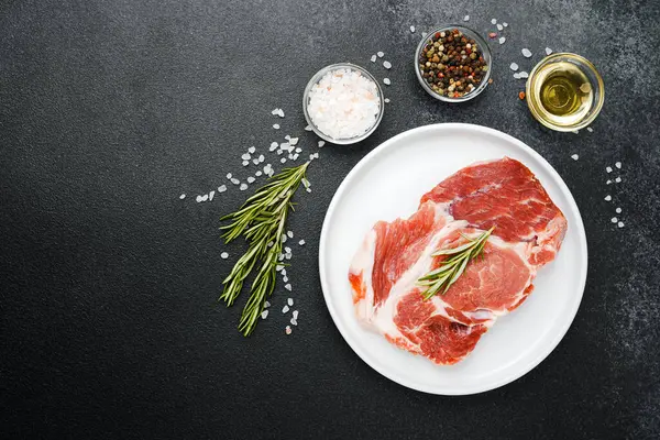 Biberiye ve baharatlı, beyaz tabakta pişmemiş biftek.