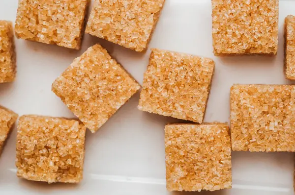 Beyaz bir yüzeye yerleştirilmiş kahverengi şeker küpleri dokularını ve şekillerini vurgular.