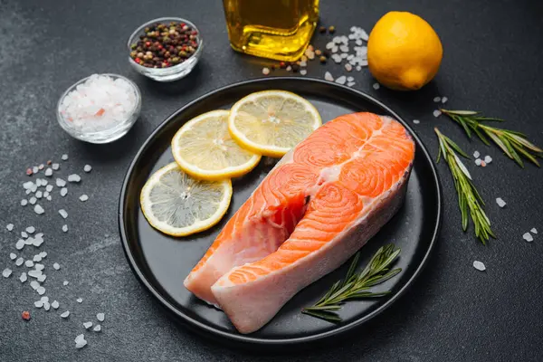 Somon filetosuna koyu bir yüzeyde limon dilimleri ve baharatlar eşlik eder..
