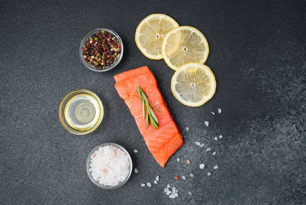 Taze somon, koyu yüzeyde limon dilimleri, baharatlar ve zeytinyağı ile düzenlenir..