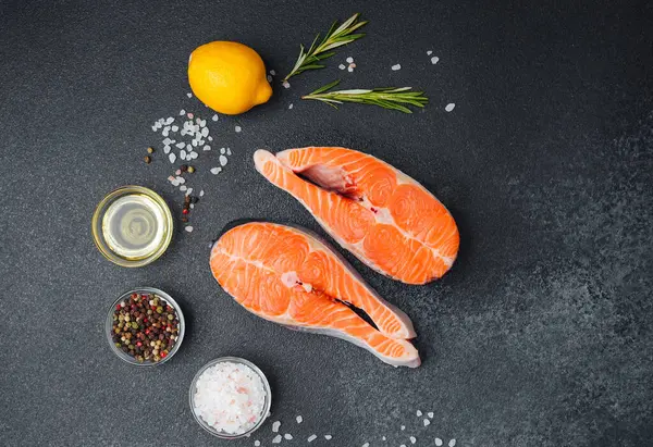 Somon fileto ve baharatlar, yakınlarda taze limon ve otlarla pişirilmek için hazırlandı..