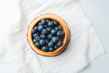 Temiz beyaz bir beze yerleştirilmiş taze yaban mersini dolu bir kase..