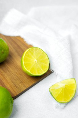 Taze limonlar yumuşak beyaz bir havlunun yanında tahta bir tahtanın üzerinde dilimlenir..
