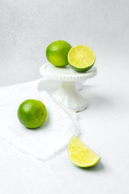 Taze yeşil limonlar beyaz bir kaidede sergilenir. Yanında da kesilmiş kireç bulunur..