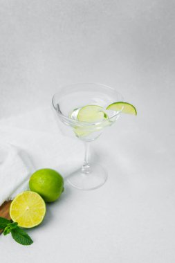 Canlı bir kokteyl, beyaz bir yüzeyde limon dilimleriyle süslenir..