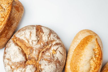 Açık bir yüzeyde üç çeşit ekmek sergilenir ve kabuklu dokuları sergilenir..