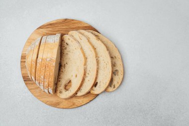 Taze pişmiş ekmek dilimlenmiş ve doğal ışık altında ahşap bir tahtada sergileniyor..