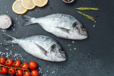 Limon biberli çiğ dorado balığı ve siyah arka planda biberiye.
