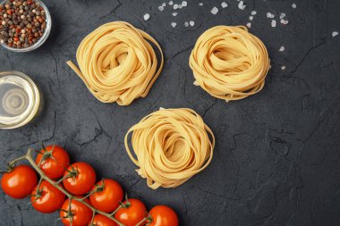 Domatesli Tagliatelle makarnası, yağ, biber ve tuz siyah desenli arka planda.