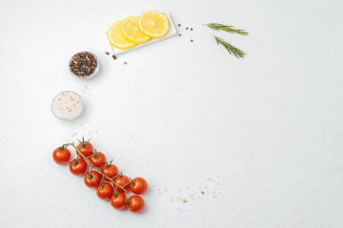Taze pişirme malzemeleri domates limonlu biberiye tuzu beyaz masada.
