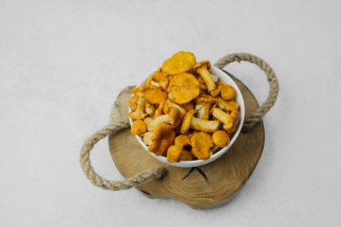 Canlı mantarlarla dolu bir kase ahşap bir tahtanın üzerinde duruyor..