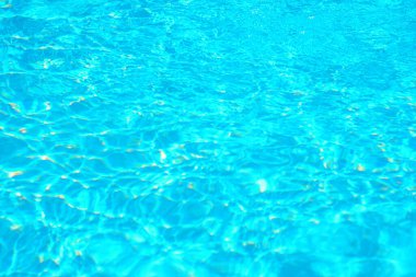 Güneş ışığı altında parlayan canlı turkuaz havuz suyu yüzeyi