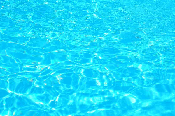 Güneş ışığı altında parlayan canlı turkuaz havuz suyu yüzeyi