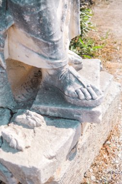 Roma ayaklarıyla antik kırık heykel tabanı ve Corinth 'te sarılı taş giysi