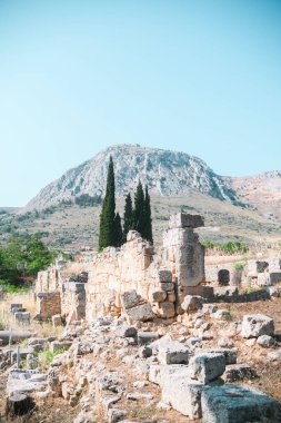 Antik Korint harabeleri üzerinde çam ağaçlarıyla tarihi dağ manzarası