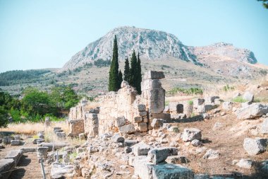 Antik Korint harabeleri üzerinde çam ağaçlarıyla tarihi dağ manzarası