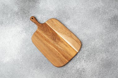 Tahta kesme tahtası gri dokulu bir yüzeye dayanır, işçiliğin altını çizer..