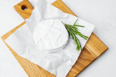 Yumuşak peynir parşömenin üzerinde duruyor ve biberiye ağacının yanında..