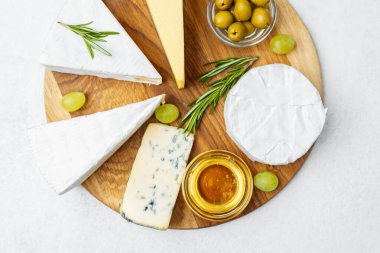 Tahtada zeytin ve balla sıralanmış çeşitli peynirler..