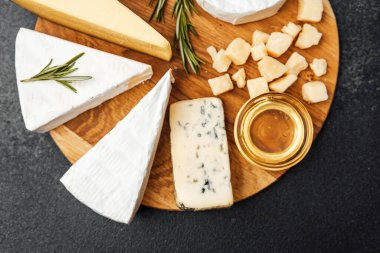 Dekoratif peynir tabağı çeşitli peynirler ve bal sunar..