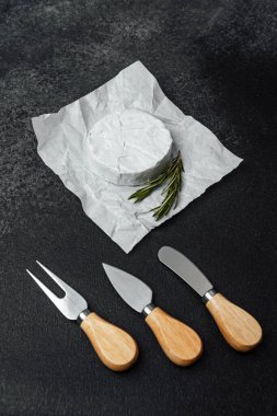 Gurme peyniri servis ve keyif için hazır otlar ve çatal bıçaklarla kağıtta oturur..