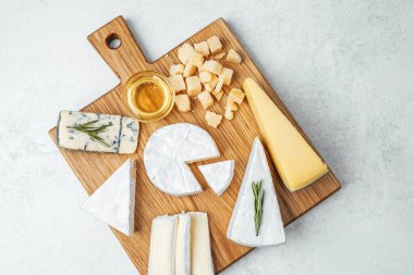 Bir servis tahtasında balın yanında güzel bir peynir seçimi..