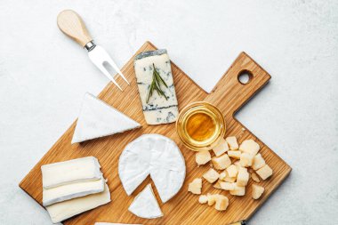 Tahtaya dizilmiş, yanında bal olan bir peynir koleksiyonu..