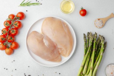 Çiğ tavuk göğsü beyaz tabakta sebzeler ve baharatlar masada!