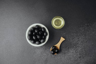 Siyah zeytinyağı ve koyu renkli zeytin yağlı arka planda.