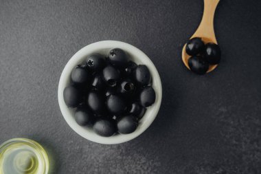 Siyah zeytinyağı ve koyu renkli zeytin yağlı arka planda.