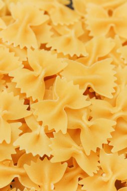 Pişmemiş farfalle makarnası düz bir yüzeyi doldurur ve eşsiz papyon şeklini gösterir..