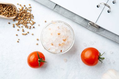 Beyaz arka planda domatesli pembe tuz ve kişniş tohumları.