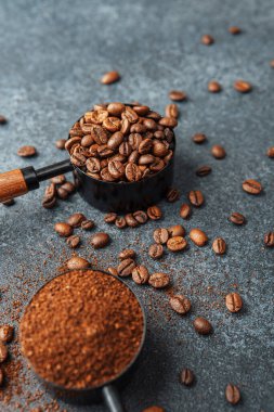 Koyu arka plandaki kepçeleri ölçmek için öğütülmüş kahve ve fasulye.